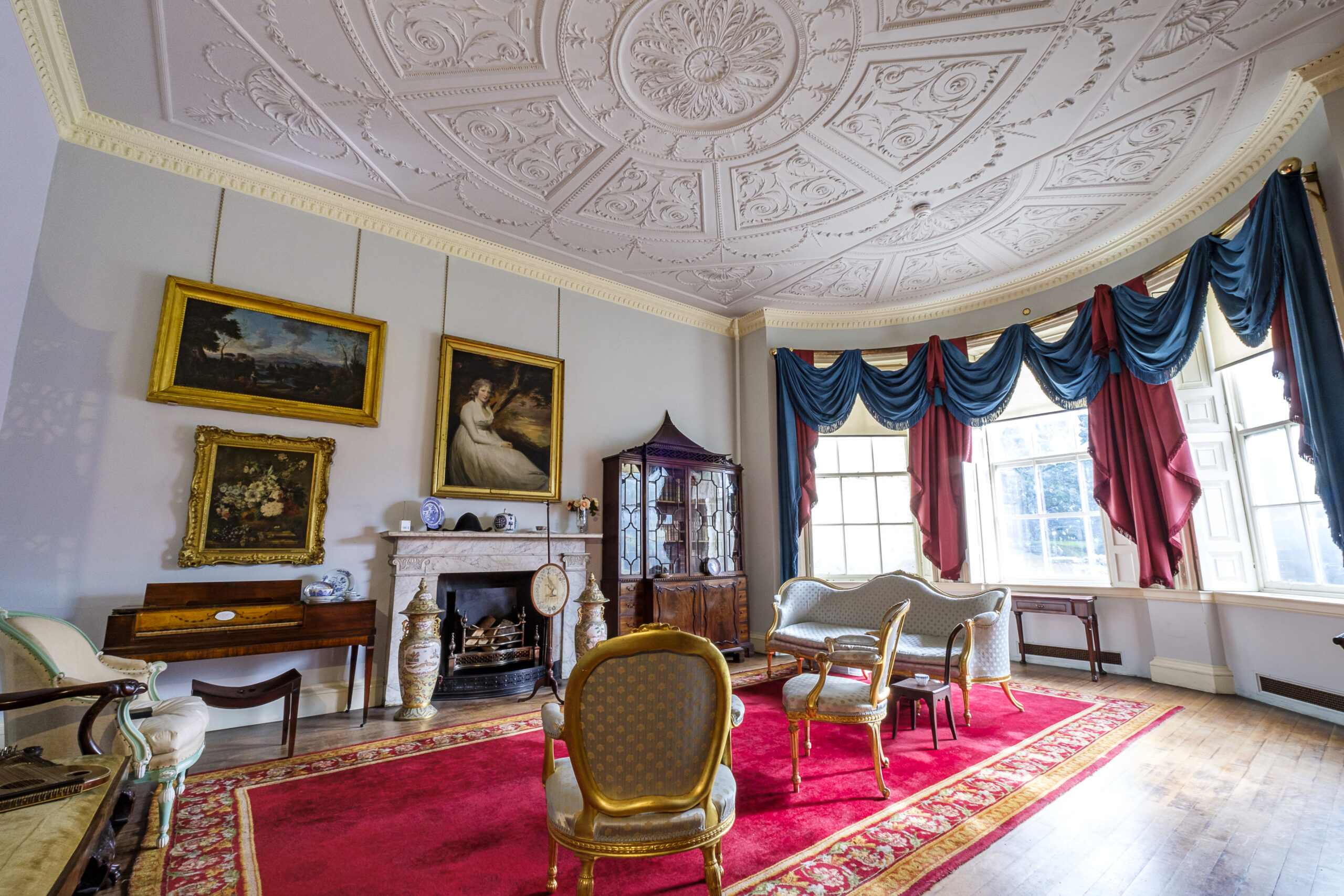 showing a georgian drawing room, light blue walls, ornate white ceiling and chippendale style furniture