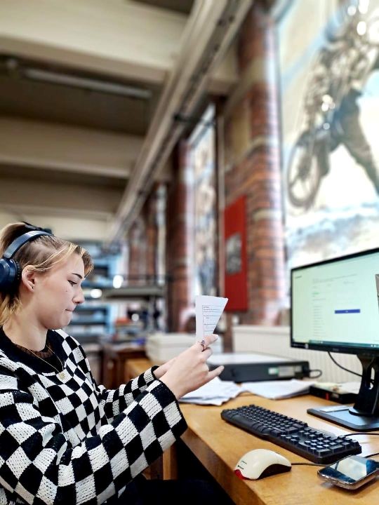 young person sat a a computer, inputting information