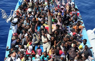 A group of 300 sub-Saharan Africans sit in board a boat during a rescue operation by the Italian Finance Police vessel Di Bartol