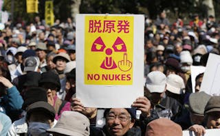 A anti-nuclear protester holds a banner saying "No Nukes" before a march by protesters in Tokyo