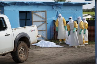 Health workers, wearing head-to-toe protective gear, prepare for work, outside an isolation unit in Foya District, Lofa County i