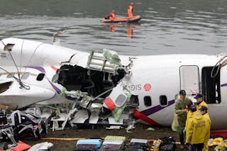 Rescue personnel search in the waters near the wreckage of TransAsia Airways plane Flight GE235 after it crash landed into a riv