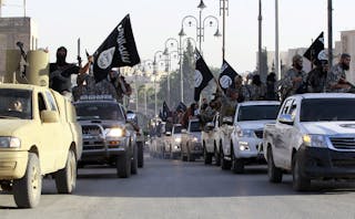 Militant Islamist fighters parade on military vehicles along the streets of northern Raqqa province