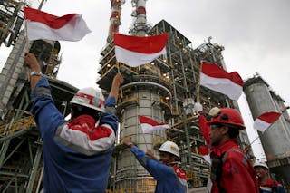 Pertamina employees wave Indonesian flags during a visit by the company's CEO Dwi Soetjipto and Indonesia's Vice-President Jusuf