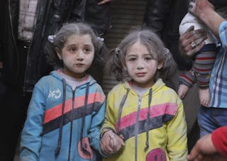 Girls who survived what activists said was a ground-to-ground missile attack by forces of Syria's President Assad, hold hands at