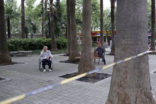 An elderly man sits in a wheelchair while relaxing at a park in Shanghai