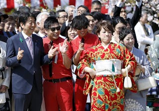 Japan's PM Abe poses with Japanese comedy duos '8.6 second bazooka' and 'Japan erekiteru union' members at a cherry blossom view