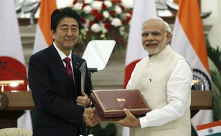 Japan's PM Abe and his Indian counterpart Modi shake hands while exchanging documents during a signing of agreement at Hyderabad