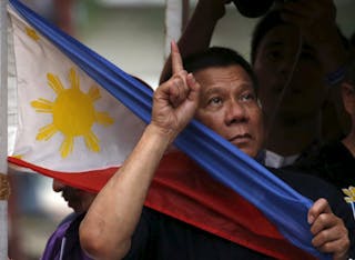 Presidential candidate Rodrigo "Digong" Duterte holds a national flag during election campaigning for May 2016 national election