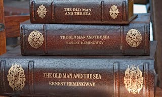 Three stacked leather bound books by Ernest Hemingway.