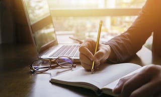 Young male student writes information from portable net-book while prepare for lectures in University campus,hipster man working