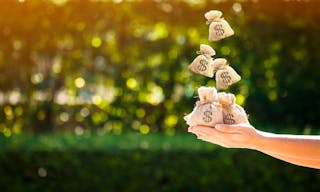 Women hands hold a money bags and dropping on the top in the public park for loans to planned investment in the future concept. 