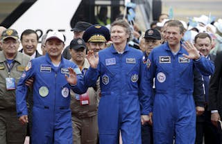 Crew members Aimbetov of Kazakhstan, Padalka of Russia and Mogensen of Denmark walk on their arrival to Astana