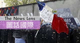 A man holds a French flag with the message, "No to the El Khomri law" in front of a line of French riot police during a protest 