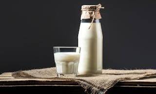 Close-up view of fresh milk in glass and jar on sackcloth — Photo by VadimVasenin