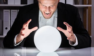 Young Businessman Looking Into The Future In A Crystal Ball In Office