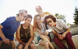 Group of teenage (16-17) friends hanging out using smartphone