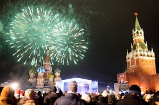 People watch fireworks explode above St Basil's Cathedral next to the Kremlin in Red Square in Moscow