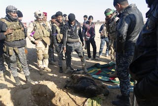 Iraqi security forces look at the body of a dead member of the Islamic State who died in clashes with Iraqi security forces on t