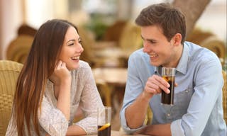 Happy couple or friends talking in a restaurant and looking each other