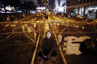 A protester sits in front of a barricade on the main street to the financial Central district in Hong Kong