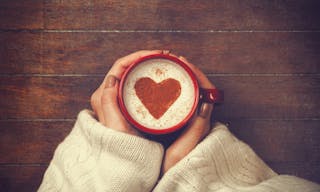 woman holding hot cup of coffee, with heart shape