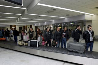 Iraqi refugees returning from Finland wait for their luggage at Baghdad airport