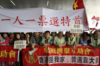 Political reform supporters stand outside the Legislative Council in Hong Kong April 22, 2015. The Hong Kong government gave lawmakers their first look on Wednesday at a long-awaited electoral blueprint for selecting the city's next leader, a plan that reflects China's desire for a tightly controlled poll despite calls for more democracy. The Chinese characters on the banner read 