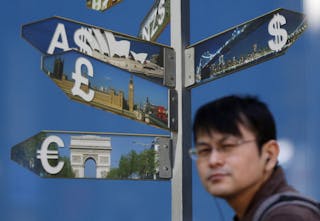 A man walks past various currency signs outside a brokerage in Tokyo