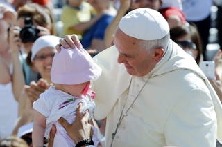 Pope Francis adjusts the hat of a baby as he arrives to lead a mass in Campobasso