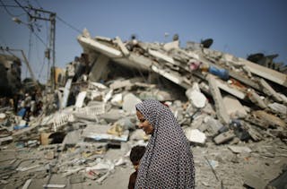 A Palestinian woman walks past the rubble of a residential building, which police said was destroyed in an Israeli air strike, i