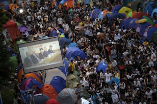 Pro-democracy protesters watch formal talks between student protest leaders and government officials on a video screen near the 