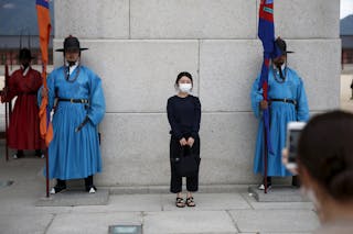 A Chinese tourist wearing a mask to prevent contracting Middle East Respiratory Syndrome (MERS) poses for photographs at the mai