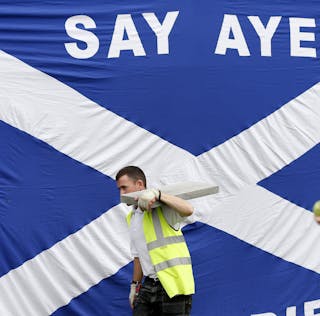 A workman walks past a Scottish saltire in Kilmarnock, Scotland