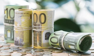 Selective focus of euro banknotes in rolls with rubber bands and coins on table — Photo by VadimVasenin