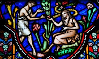 BRUSSELS, BELGIUM - JULY 26, 2012: Adam and Eve eating the Forbidden Fruit in the Garden of Eden on a stained glass window in th