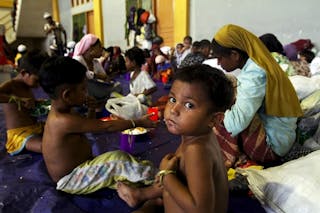 A child, believed to be Rohingya, eats inside a shelter after he was rescued along with hundreds of others on Sunday from boats 