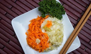 fermented vegetables o n a white plate arranged in a ting hand concept