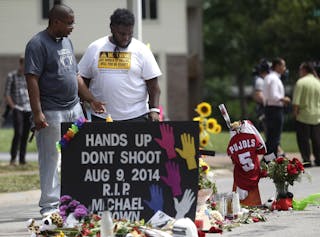 Two men stand over the makeshift memorial for Michael Brown in Ferguson