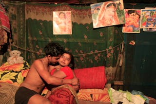 Seventeen-year-old prostitute Hashi embraces a Babu, her "husband", inside her small room at Kandapara brothel in Tangail, a nor