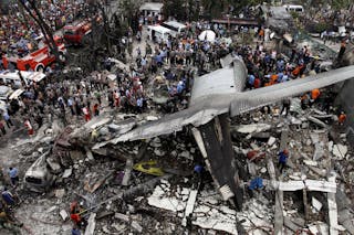 Security forces and rescue teams examine the wreckage of an Indonesian military C-130 Hercules transport plane after it crashed 