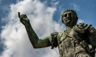 ROME/ ITALY JULY 2017 - Bronze statue of emperor Caesar Nervae Trajan, Forum of Caesar Nervae Trajan in the background