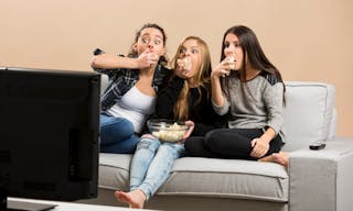 Teenage girls watching horror movie with popcorn