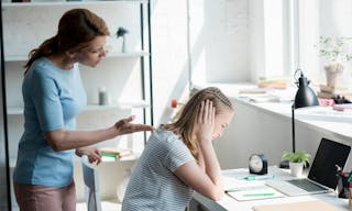 Depressed teen daughter sitting at work desk at home while her mother yelling at her — Photo by IgorVetushko