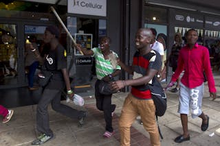 South African men run from police as rioting and looting was quelled during anti-foreigner violence in Durban