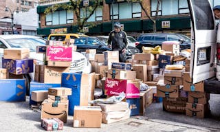 New York City, USA - October 30, 2017: Delivery man with many boxes in NYC by BH photo video store, van truck unloading amazon p