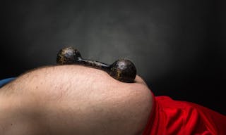 Old black dumbbell on the fat belly