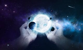 Two hands holding the sun and planets in the universe