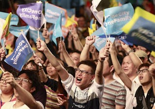 Supporters wave flags after Taipei mayoral candidate Ko Wen-je won the local elections, in Taipei