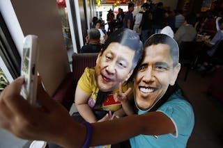 Members of activist Party List group "Akbayan" wearing picture cut-out masks of U.S. President Barack Obama and China's Presiden